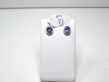 une paire de boucles d'oreilles en saphir bleu et diamants, présentée sur un présentoir blanc