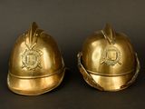 pair of brass fireman ' s helmets on a black background