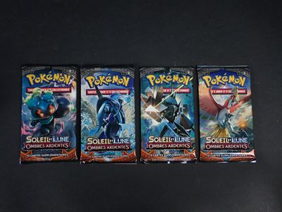 trois paquets de cartes à collectionner Pokémon posés sur une surface noire