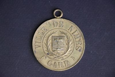 a silver medal on a blue surface with a black background
