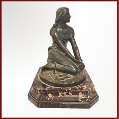 une statue en bronze représentant une femme assise sur un socle en marbre