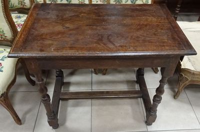 a wooden table with two chairs and a couch in the background