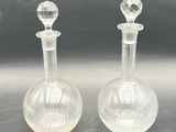 pair of clear glass decanters sitting on top of a table