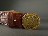 an old belt with a brass buckle and a medallion on it