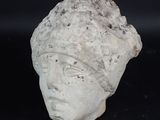 une tête de femme en pierre coiffée d'un chapeau
