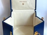 a small blue suitcase with a gold handle on a white surface