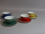 quatre tasses et soucoupes sont alignées sur une surface blanche