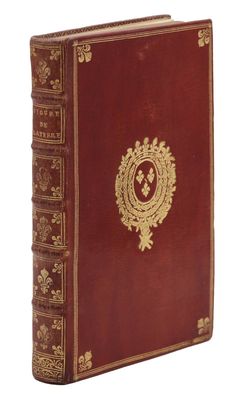 un vieux livre rouge aux tranches dorées et orné d'un emblème doré sur la couverture