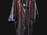 an old coat hanging on a hanger on a black wall