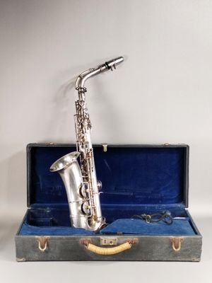 un vieux saxophone argenté dans un étui bleu sur fond blanc