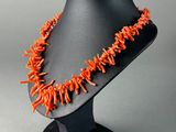 a close up of an orange necklace on a black mannequin