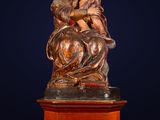 an antique statue of a woman holding a child on top of a wooden pedestal