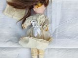 a doll with long brown hair laying on a white sheet