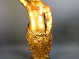gold statue of a child holding a golden object in his hand