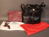 un sac à main noir et un portefeuille rouge posés sur une table
