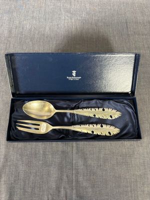 two gold spoons and a fork in a black box