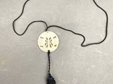 un pompon noir orné d'un disque blanc sur lequel figure une inscription en chinois