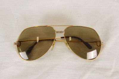 sunglasses on a white cloth with a reflection of a person ' s face