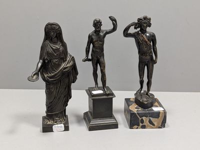 trois statues en bronze représentant une femme et un homme, posées sur des socles en marbre