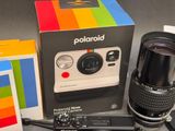 a polaroid camera next to a box and a camera lens