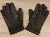 a pair of brown leather gloves sitting on top of a wooden table