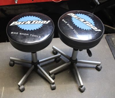 two black stools sitting on top of a table next to a red car