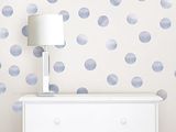 a white dresser with a lamp on top of it in front of a wall with blue polkas