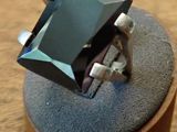 a ring with a black stone in it on a wooden stand