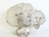 a sculpture of three faces on a rock with a white background