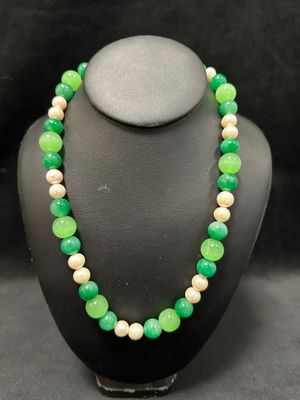 a green and white beaded necklace on a black mannequin