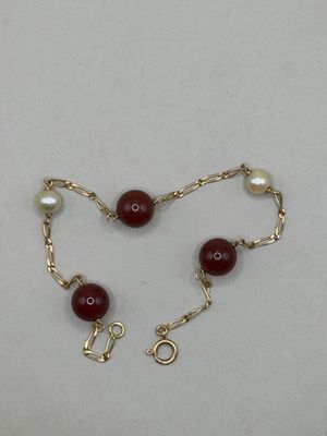 un gros plan sur un bracelet à chaîne en or orné de perles rouges
