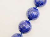 a close up of a strand of blue beads on a white surface