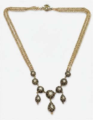un collier en or orné de perles noires et blanches montées sur une chaîne en or
