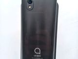the back of a black cell phone sitting on top of a white surface