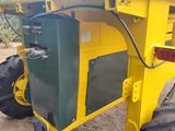a yellow tractor with a green container attached to it ' s back
