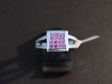 a pink diamond ring sitting on top of a black table