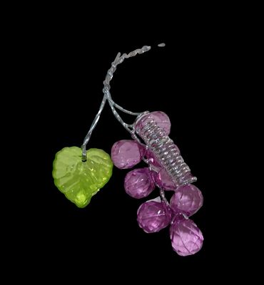 purple and green glass bead with a green leaf on a black background