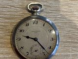 une montre de poche en argent posée sur une table en bois