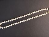 a close up of a white beaded necklace on a black surface