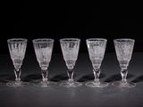 six empty wine glasses lined up on a black surface