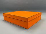 un gros plan d'une boîte orange posée sur une surface blanche