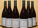 six bouteilles de vin sont alignées sur une étagère en bois