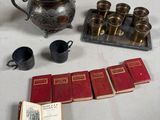 a silver teapot, a book, cups, and a teapot on a table