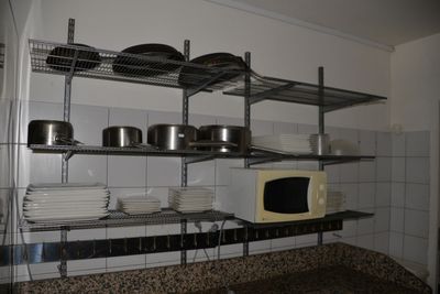 des étagères sur lesquelles sont posées des casseroles et des poêles, dans une cuisine équipée de plans de travail en granit