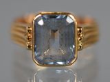 une image d'une bague en or avec une pierre en topaze bleue