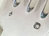 a close up of a silver fork with a diamond on it