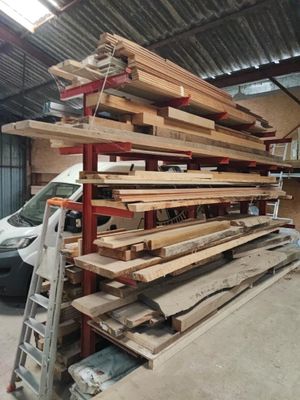 une grande pile de bois dans un garage, à côté d'une voiture