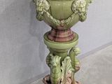 a green vase on a pedestal with a bird on it