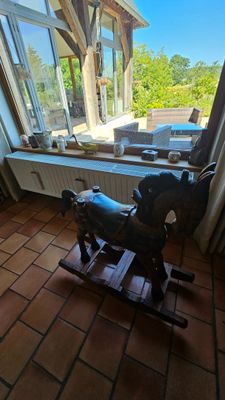 un cheval à bascule devant une fenêtre, dans une pièce