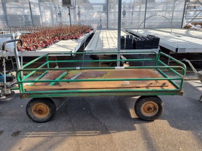 un chariot vert sur lequel est posée une table en bois, dans une serre
